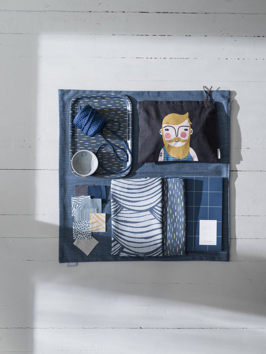 Blue FRANK toiletry bag with multiple compartments, stainless steel cup, and unique decorative items reflecting. - FRANK Toiletry Bag