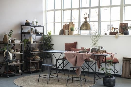 Cozy dining space featuring a brick-red doppeltgewebt plaid draped over a black metal table, showcasing einzigartig Wohndeko . - Plaid doppeltgewebt ziegel