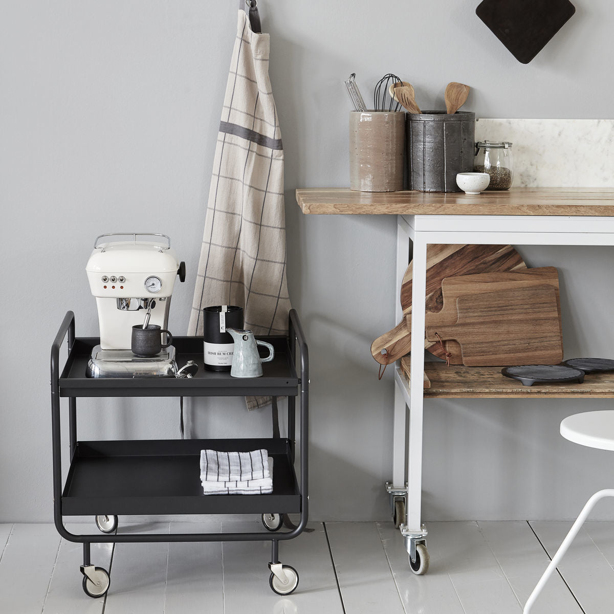 Beige apron Opa Sand with plaid pattern hanging beside a black cart, enhancing individueller Stil and einzigartig Wohndeko. - Apron Opa Sand, one size