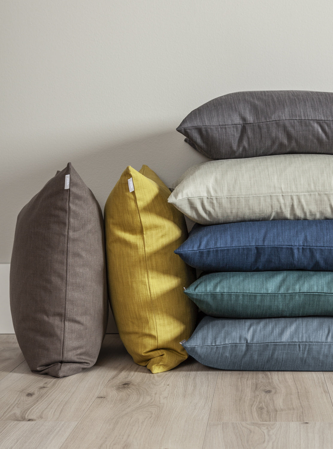 Stack of soft grey, blue, green, yellow, beige, and brown cushion covers showcasing einzigartig Wohndeko and individueller. - SLÄT Cushion Cover grey