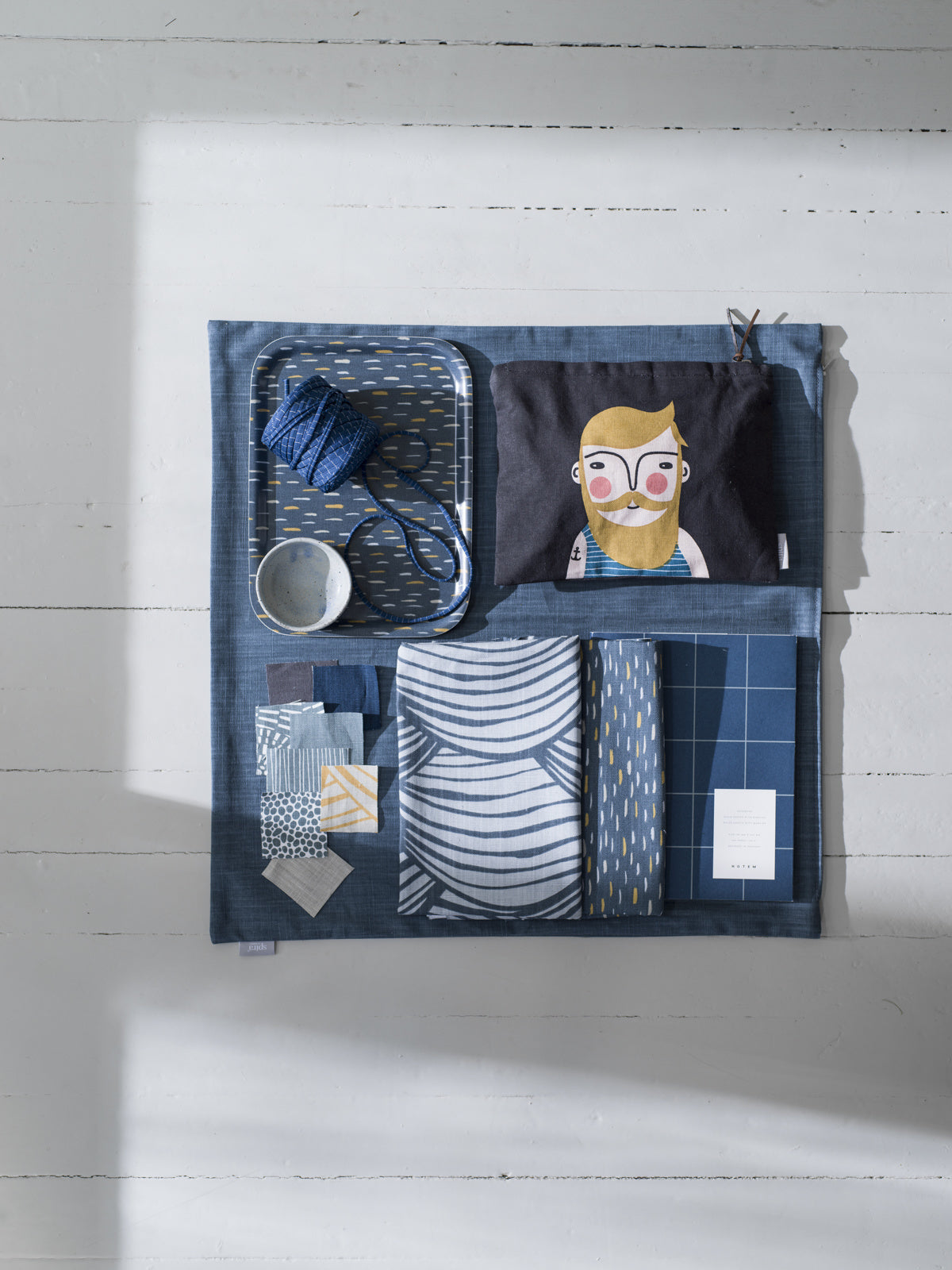 Blue FRANK toiletry bag with multiple compartments, stainless steel cup, and unique decorative items reflecting. - FRANK Toiletry Bag